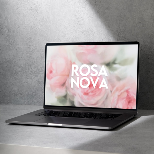 Ordinateur portable posé sur une surface en pierre grise, affichant l’inscription « ROSA NOVA » sur un fond floral pastel composé de roses roses et blanches légèrement floutées. L’image évoque la douceur, la transformation et la beauté du féminin sacré. Atmosphère apaisante et inspirante, symbole de renaissance et d’ouverture du cœur.